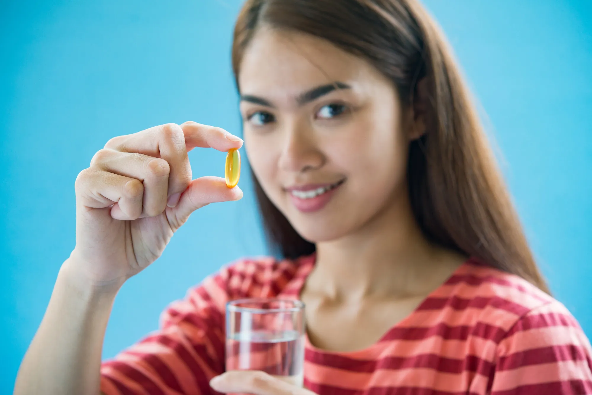 Woman taking a vitamin supplement with water, illustrating a Vitamin Store in Jacksonville, Florida.