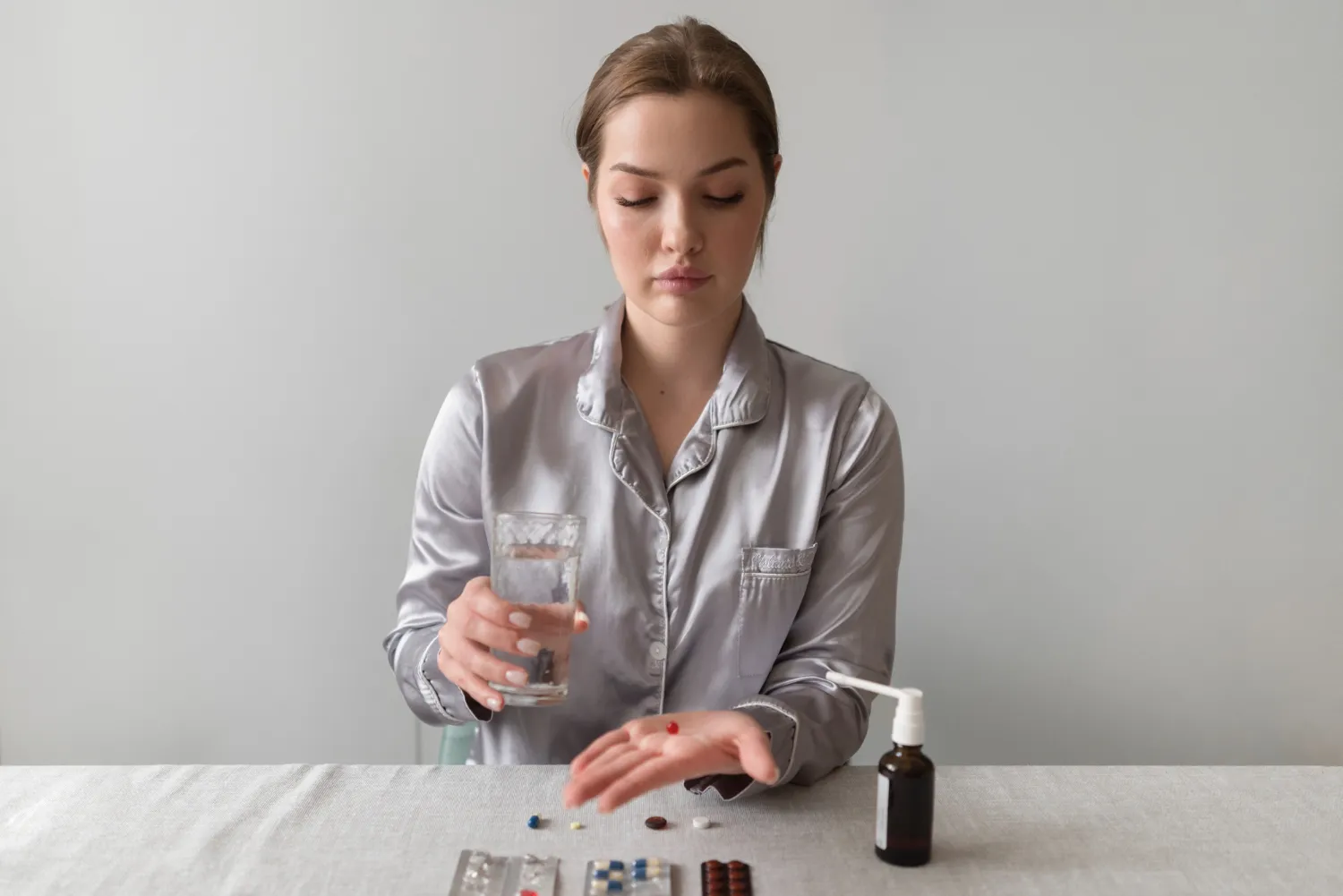 Woman taking a pill with water, representing a Vitamin And Supplement Store.
