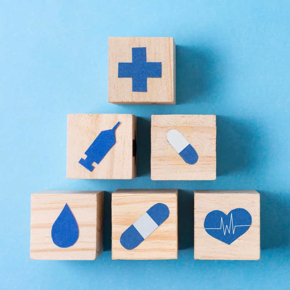 Wooden blocks featuring medical symbols, including a first-aid cross, syringe, pills, blood drop, and heart monitor, representing essential Durable Medical Supplies and healthcare products.