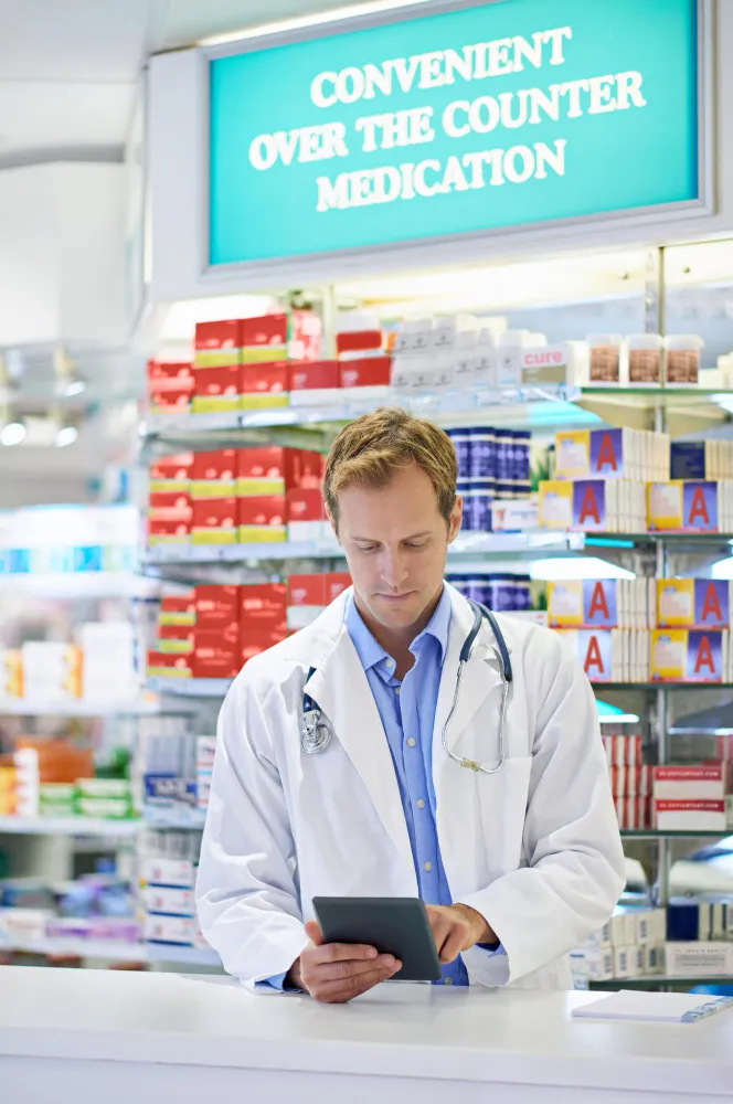 Pharmacist reviewing medications and discussing a generic drug plan in a pharmacy.
