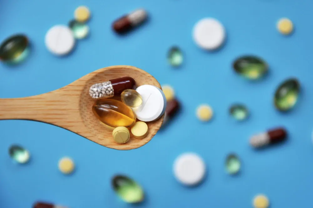 Close-up of assorted capsules and softgels on a spoon, highlighting immune boosting vitamins and essential vitamin supplements for supporting overall health