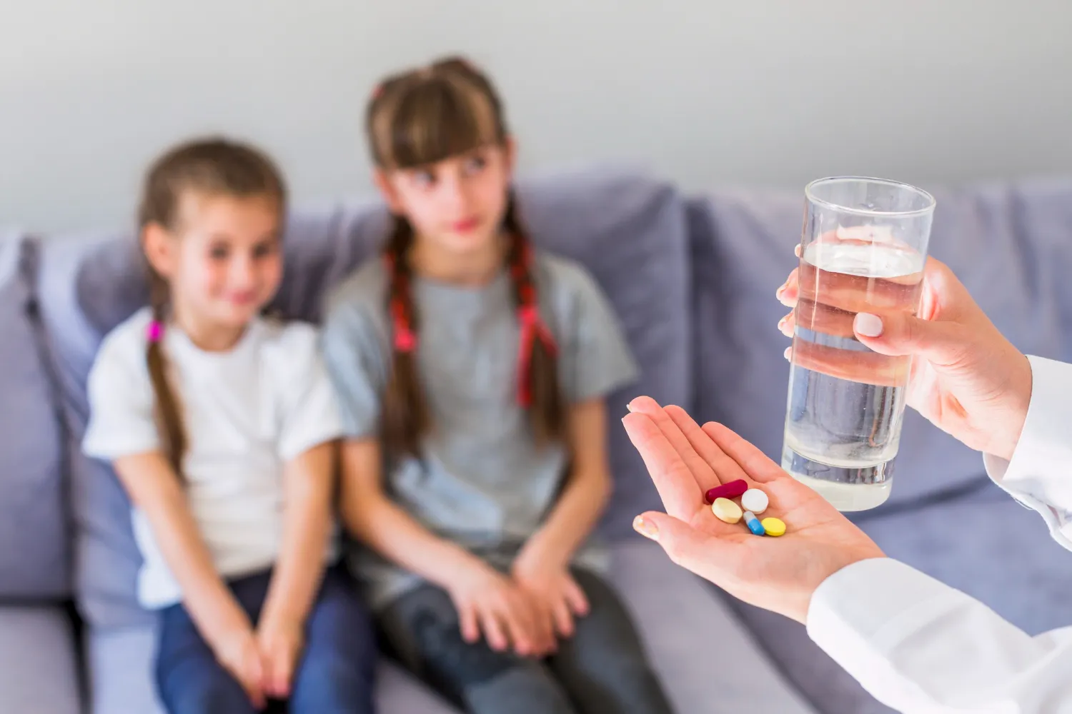 Caregiver offering prescribed pills with water to children, highlighting proper use of special medicines, secure special packaging, and safe administration of prescriptions medications for effective treatment