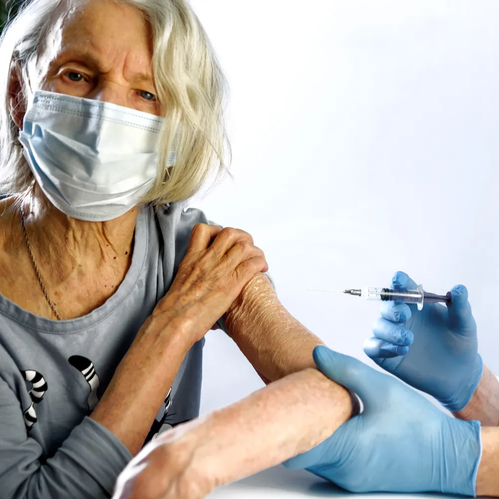 Older adult receiving a vaccine from a healthcare professional during an adult immunization appointment at a pharmacy offering immunization near me services.
