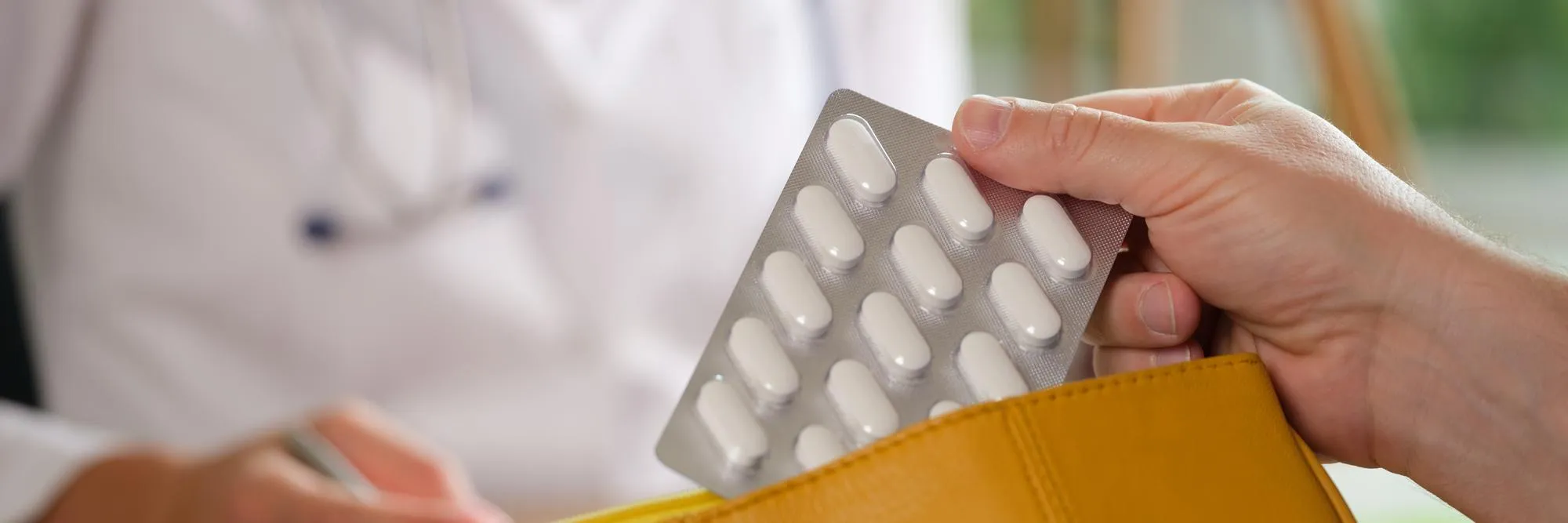 Patient receiving a blister pack of prescription medication from a healthcare provider, illustrating prescription synchronization for convenient, coordinated monthly medication refills.