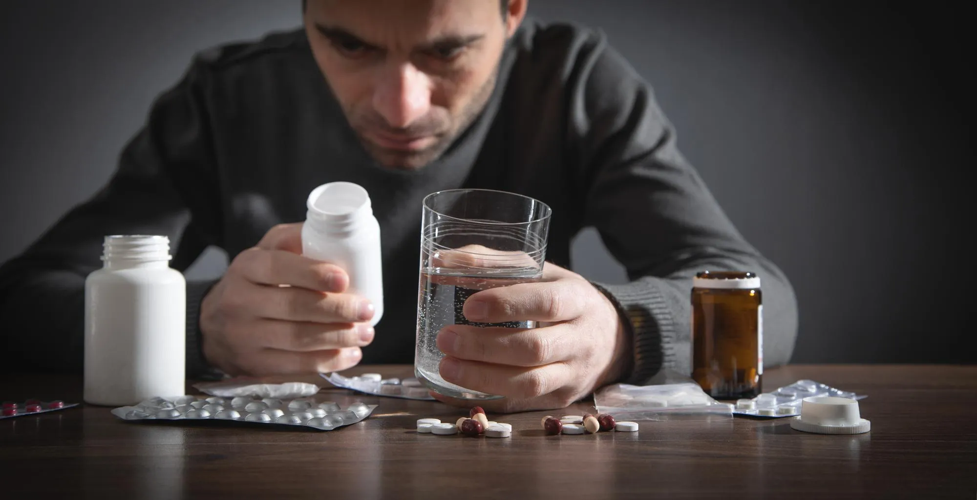 Patient taking multiple medications with water, illustrating the importance of pharmacy medication management.