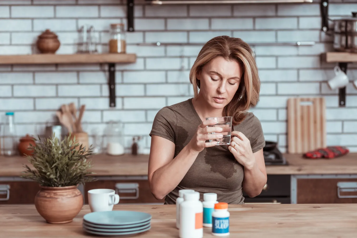 A woman taking supplements with water, illustrating considerations around daily multivitamin use and choosing the right supplements.